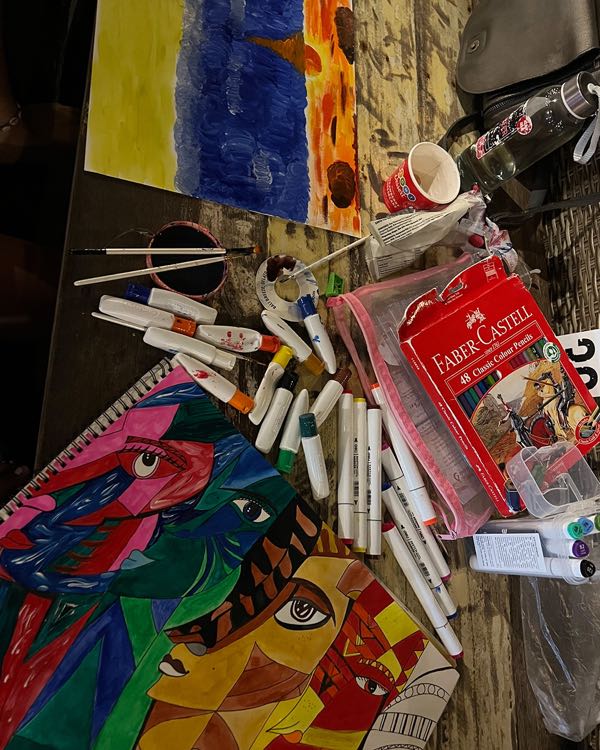 Colourful drawings, markers and paint brushes spread across a table