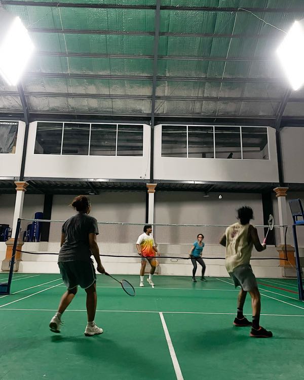 Friends playing doubles badminton on an indoor court