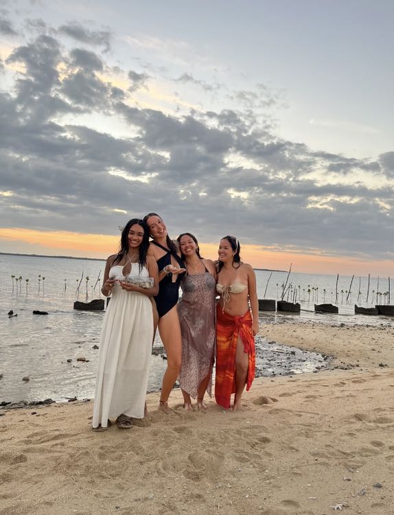 Four friends standing on the beach at sunset