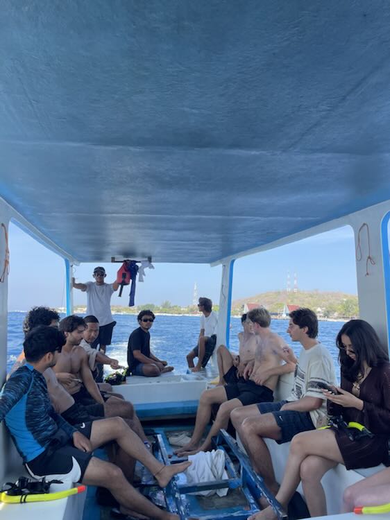 A group of friends sitting in the shade on the deck of a boat at sea