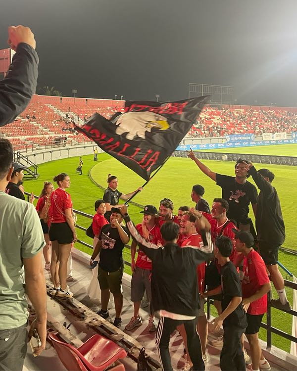 Football fans waving a large flag in the stands of a stadium