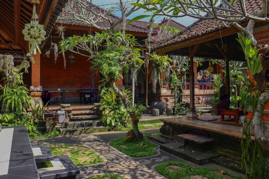 A traditional Balinese courtyard with garden paths, plants and open pavilions