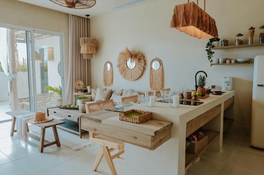 A bright open-plan kitchen and living area with rattan lamps and natural wood