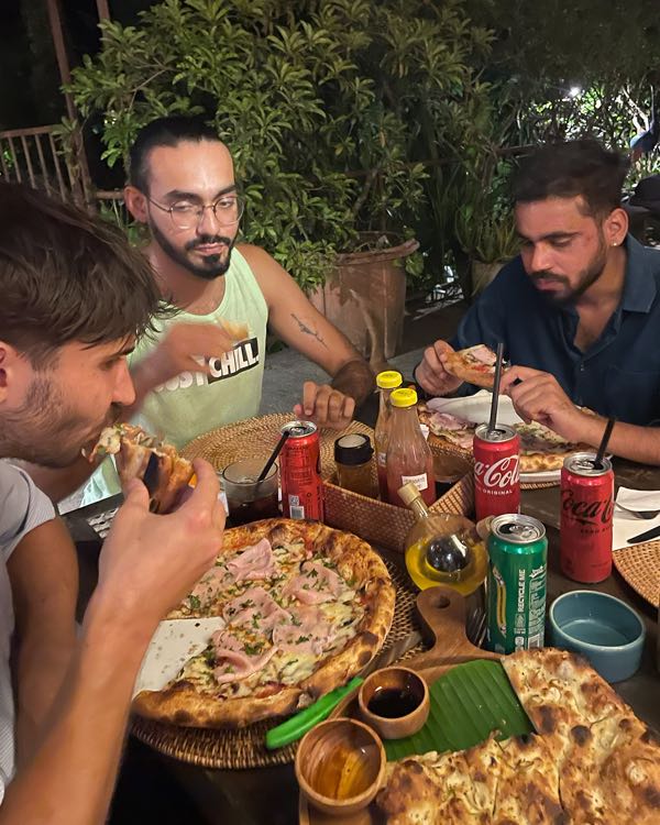 Friends sharing pizzas and drinks around a table outdoors