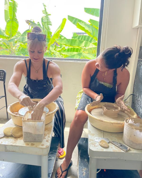 Two women shaping clay on pottery wheels