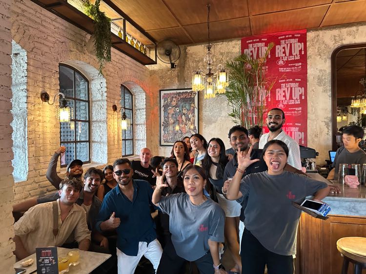 A cheerful crowd of friends posing together inside a busy café-bar