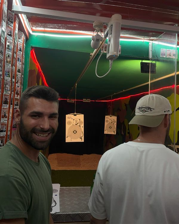 Two people at an indoor shooting range with paper targets in the lanes behind them