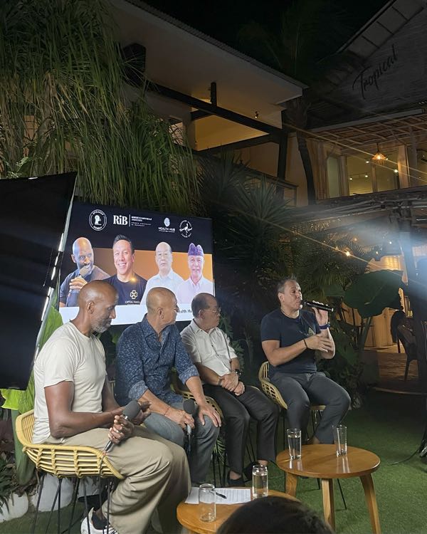 Four speakers in conversation on stage at an evening panel event